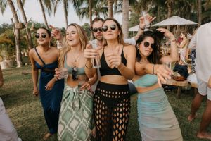 Group of wedding guests celebrating outdoors with palm trees in background.