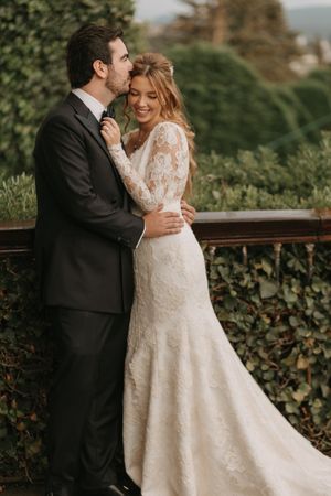 Couple in wedding attire share intimate moments against a lush green backdrop.