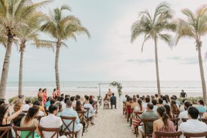Beachfront wedding ceremony setup with palm trees and ocean views in tropical paradise.
