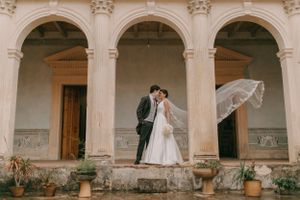 A classic stone colonnade with arched architecture creates an elegant wedding venue backdrop.