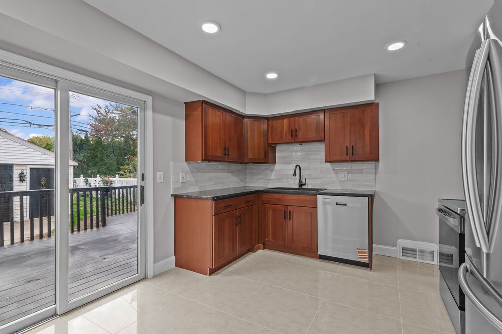 Modern kitchen with cherry wood cabinets, granite countertops, stainless steel appliances, and sliding glass door to deck.