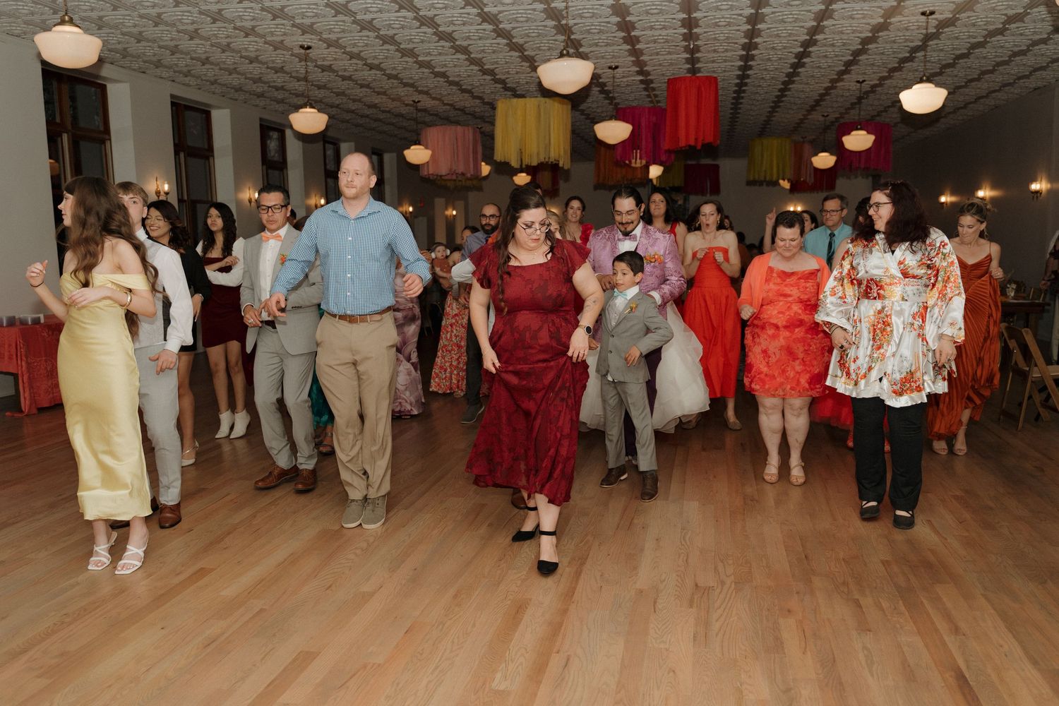 Guests dancing joyfully in a decorated ballroom during a festive celebration or wedding reception.
