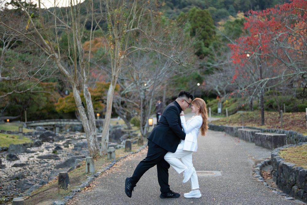 Couple dancing and dipping on a tree-lined autumn park path in Japan.