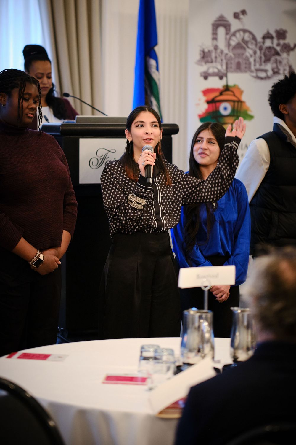 Young woman speaks into microphone at Indian Society of Calgary Anti Racism Leaders Convention podium.