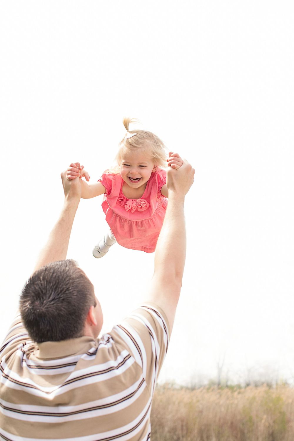 Family photo of father swinging little girl in air at Kensington Metropark in Milford, Michigan by South Lyon family portrait photographer