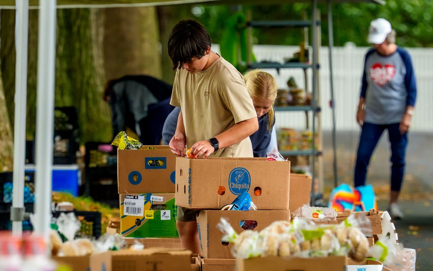 Young volunteers packing boxes of food at a Cocoa Packs community event, by Deanna Fox, SportsFox Photography, based in Hershey PA