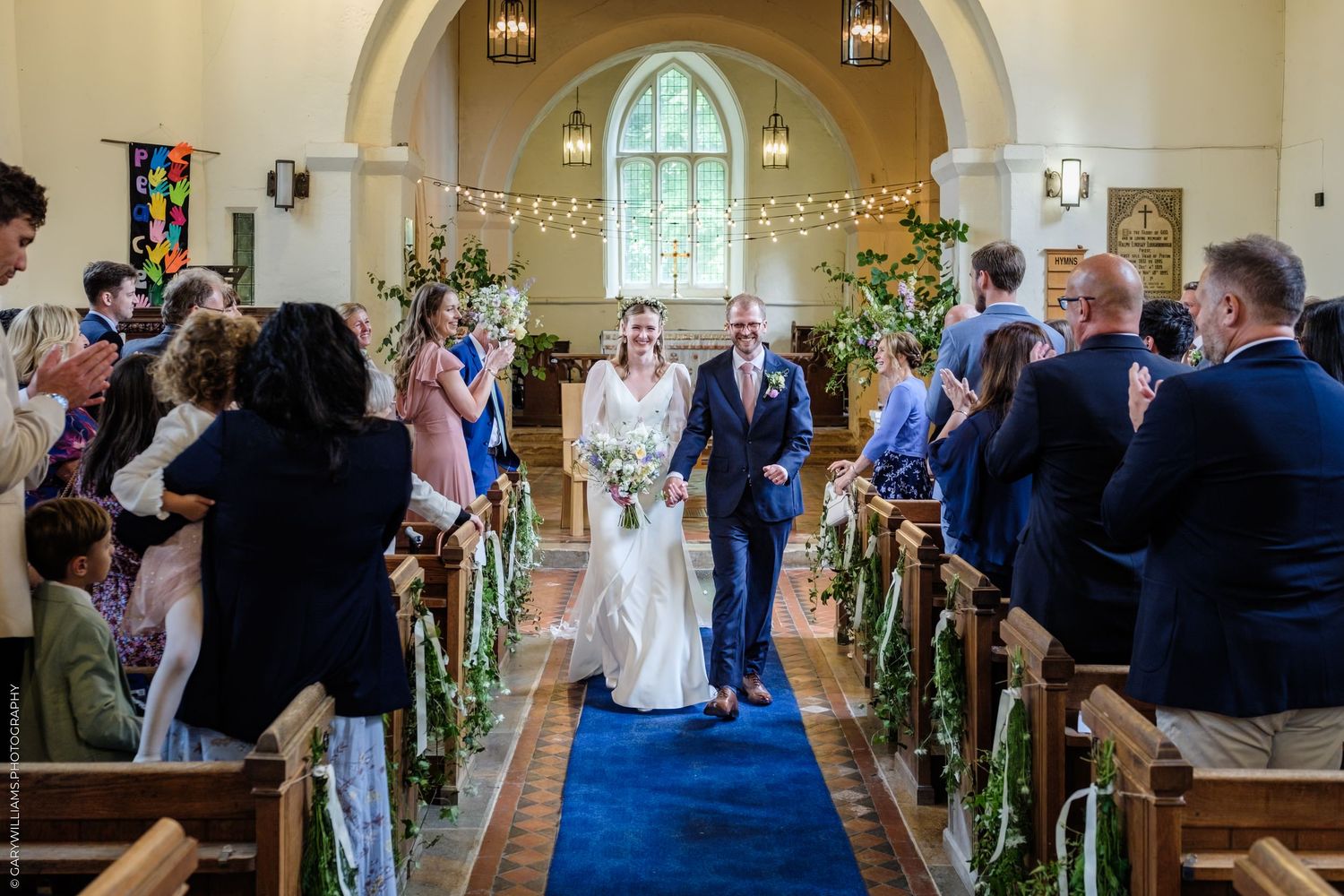 Bride and groom walk down the aisle of a decorated church after their wedding ceremony.