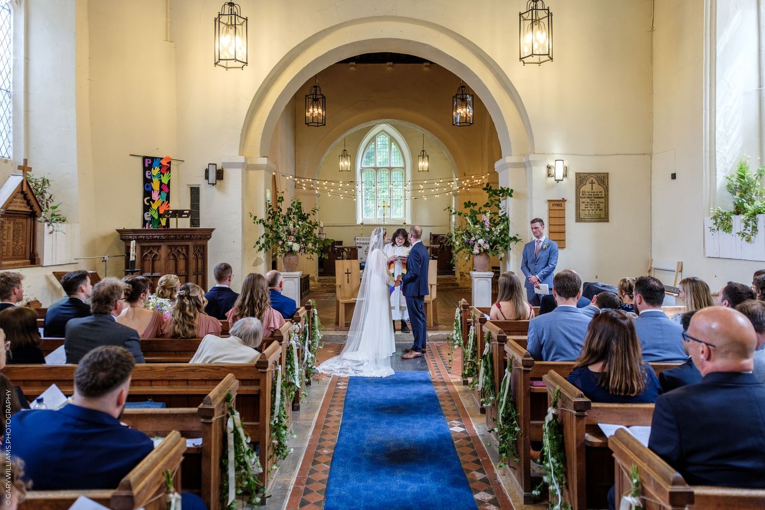 A wedding ceremony in a bright church with guests seated in pews as the couple stands at the altar.