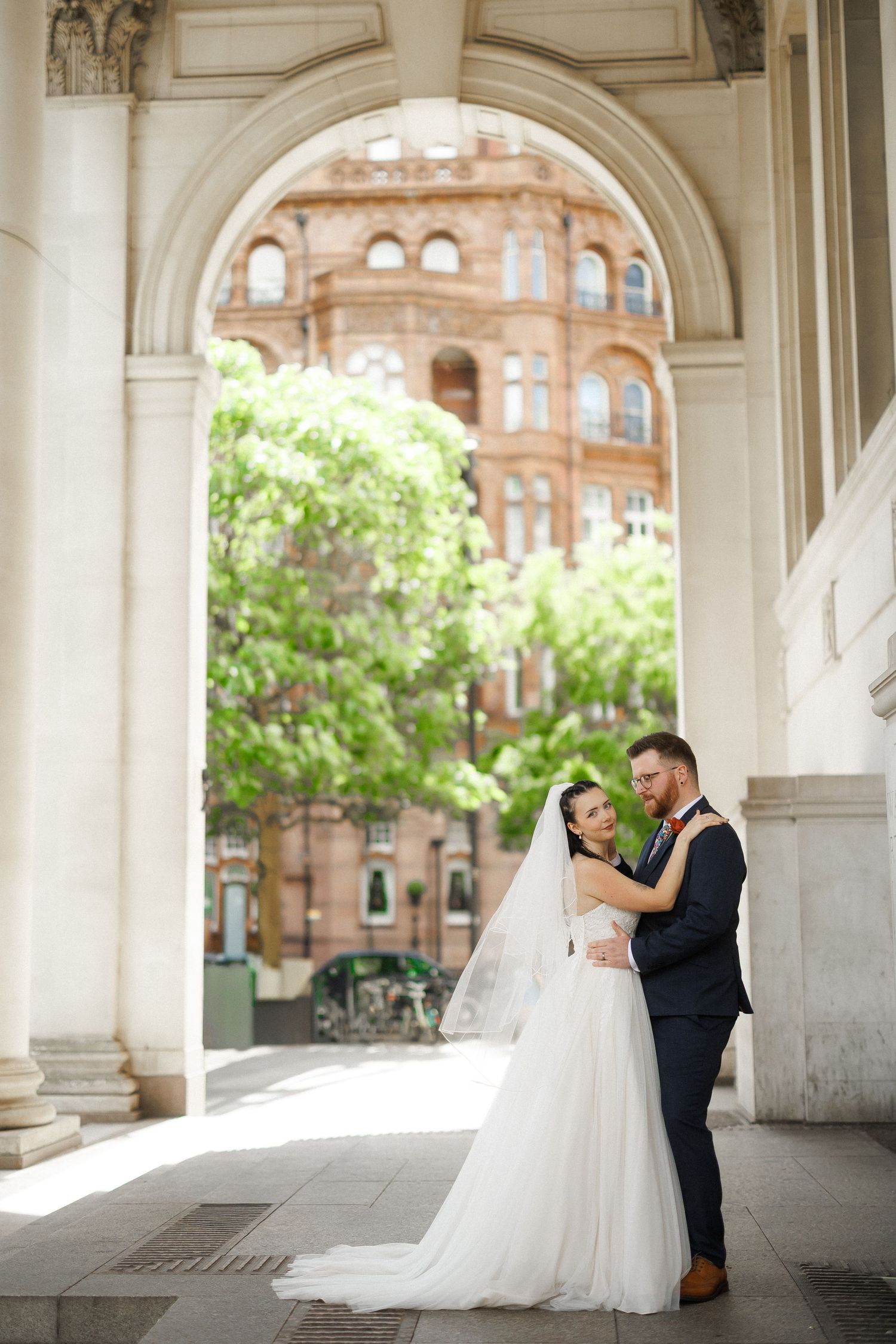 Newlywed couple walks down the aisle together at an indoor wedding ceremony with guests standing and white chiavari chairs.