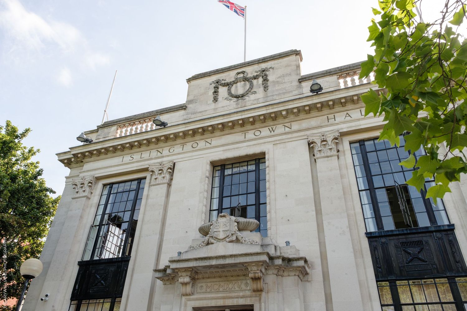 Islington Town Hall exterior with Union Jack flag, classical architecture, and ornate stone facade on a sunny day.