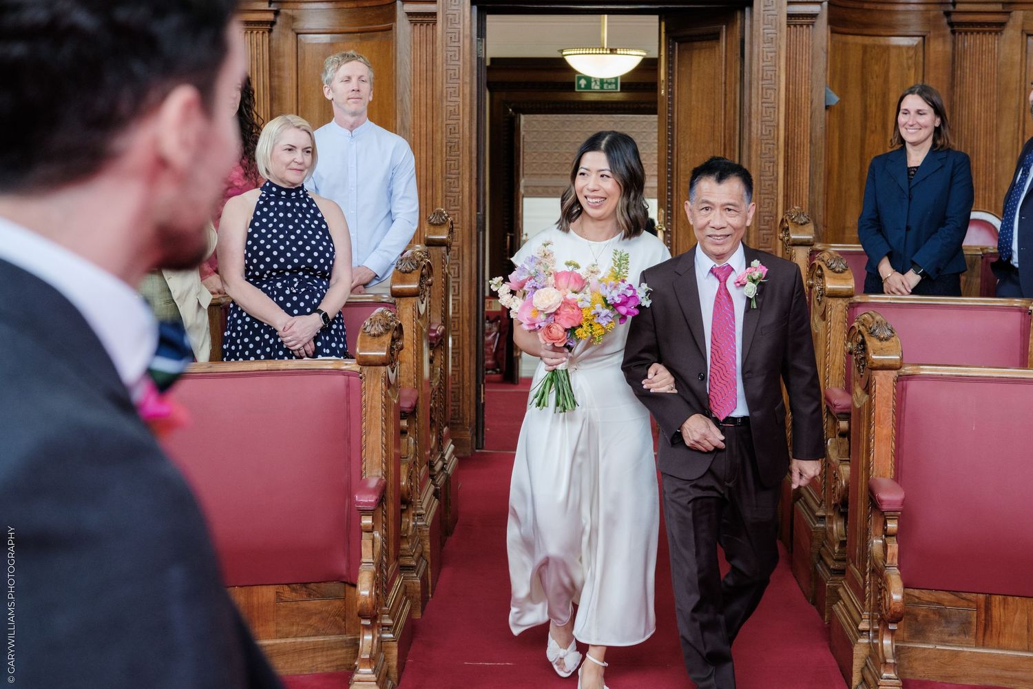 Bride walking down the aisle with her father at Islington Town Hall registry office wedding ceremony.
