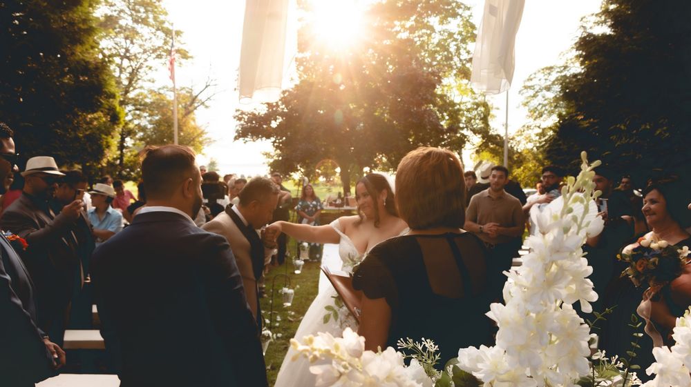 Bride walks down the aisle in golden sunlight at a beautiful outdoor wedding ceremony.