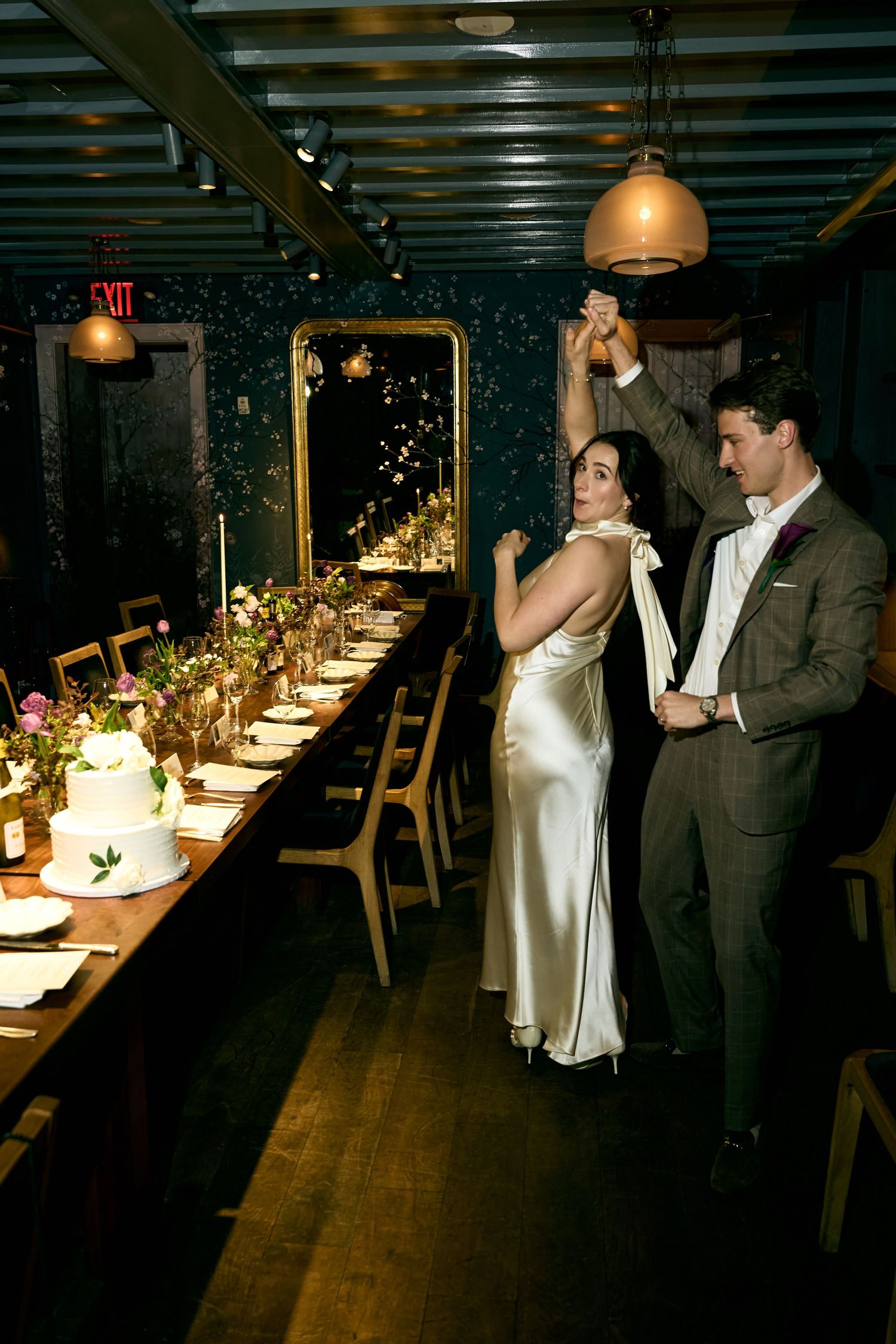 Bride and groom share a dance at elegant wedding reception with long decorated table, candles, and floral centerpieces.
