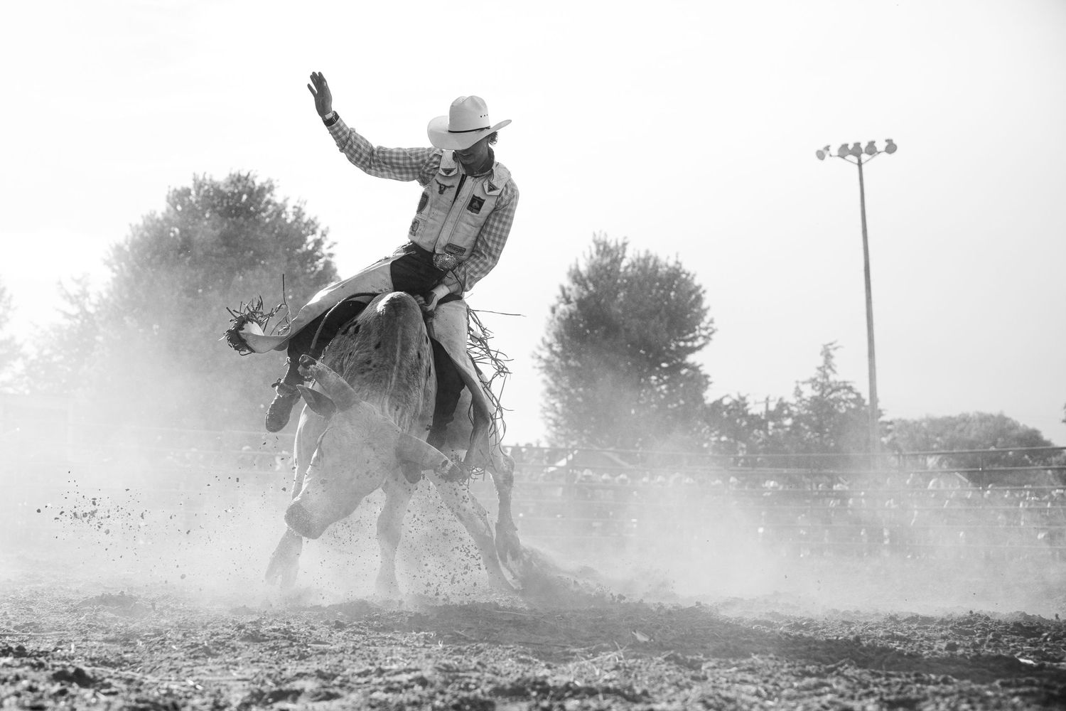 Bull rider in a dusty arena at an amateur event