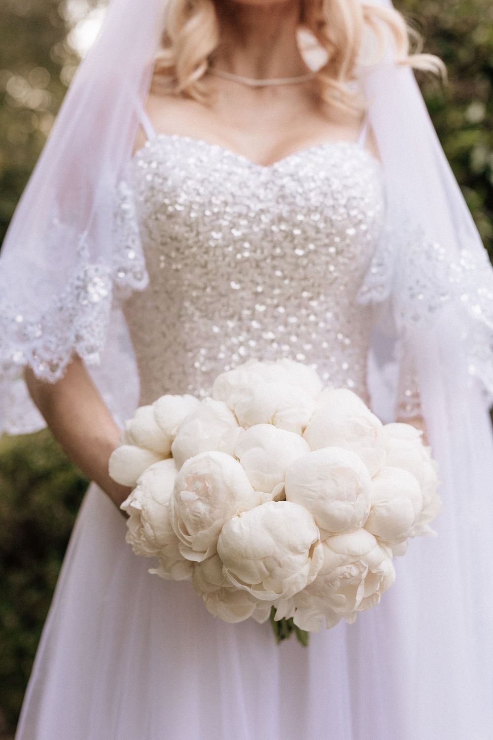 Bridal bouquet of peonies shown in elegant backyard wedding