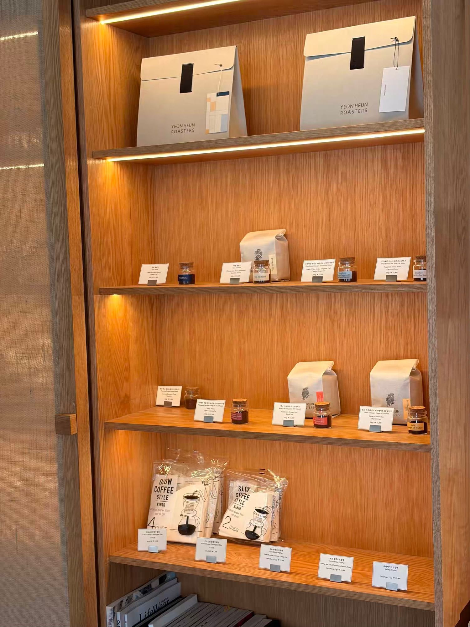 Wooden retail display shelves with LED lighting showcasing coffee products, gift boxes, and packaged goods in a modern store.