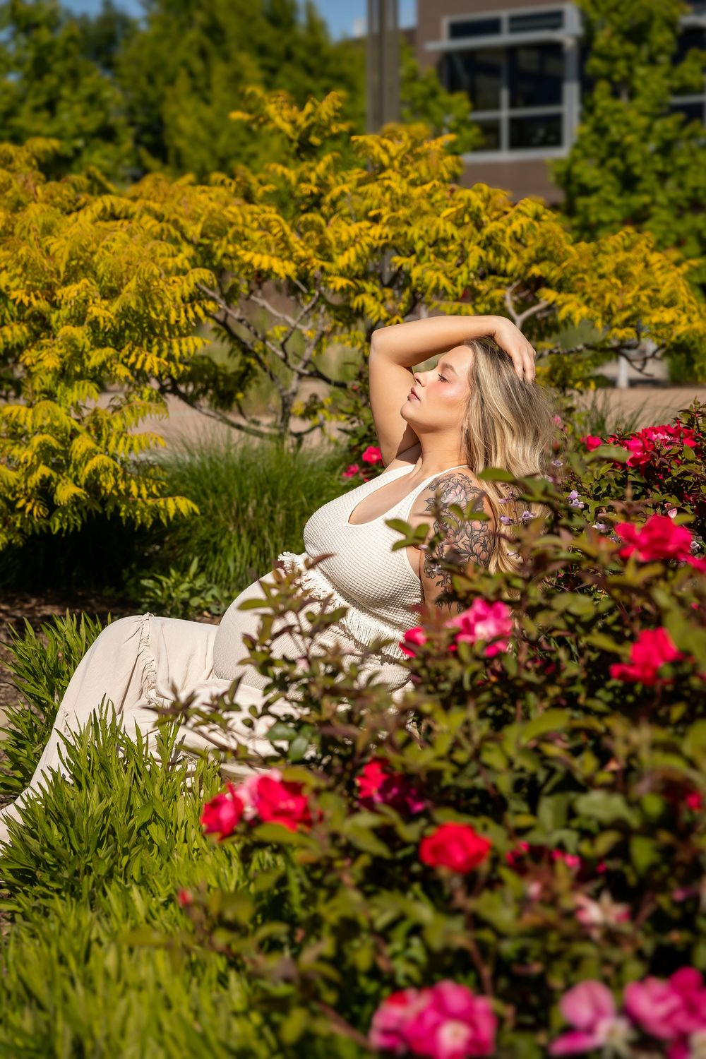 maternity photo woman sitting in flower bed in direct sunlight at Scentsy Commons Meridian Idaho Milestones Portraits