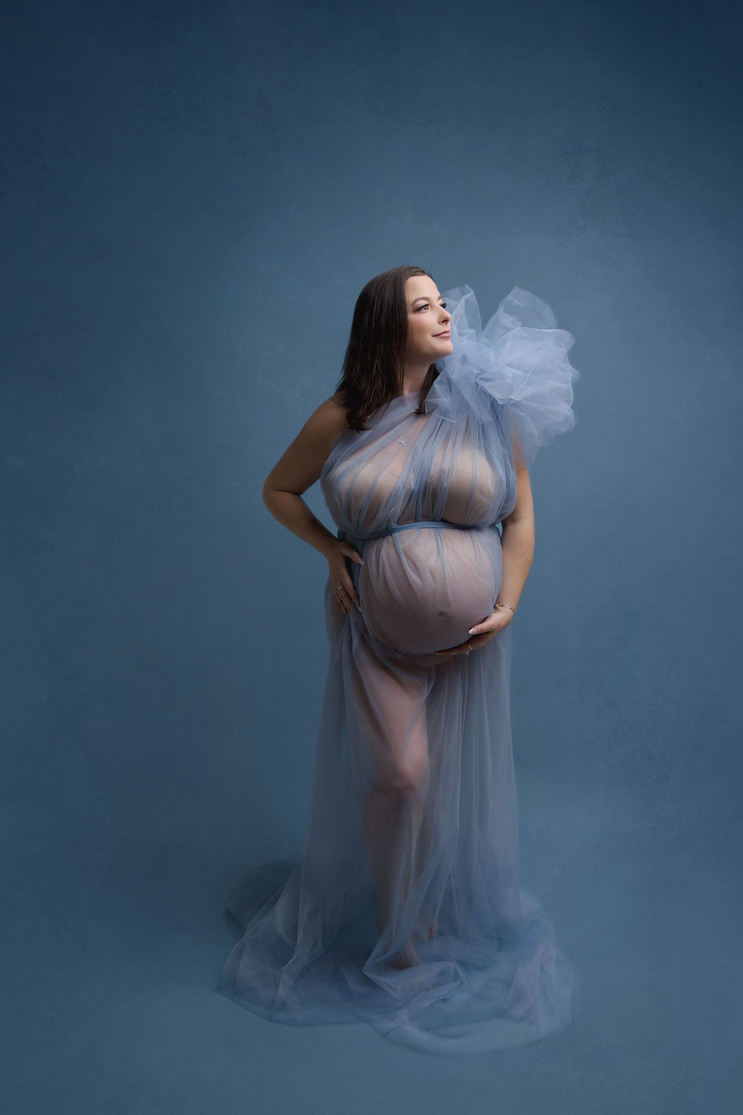Woman in ruffle lace topped, off shoulder, light blue dress with buttons up the belly, in a field.