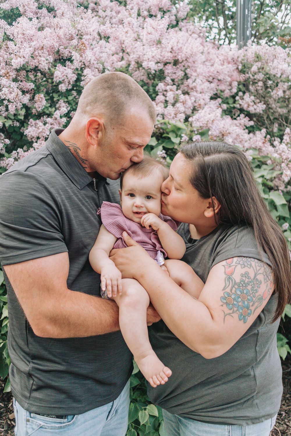 Tender family moment captured against blooming pink cherry blossoms in springtime.