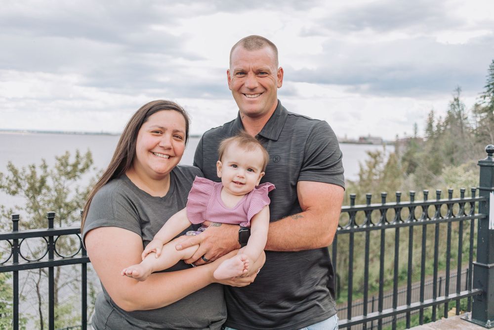 Family portrait taken on an overlook with water and trees visible in background.