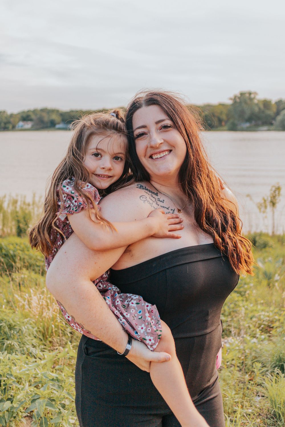 A heartwarming lakeside portrait showing affection and joy against a serene water backdrop.