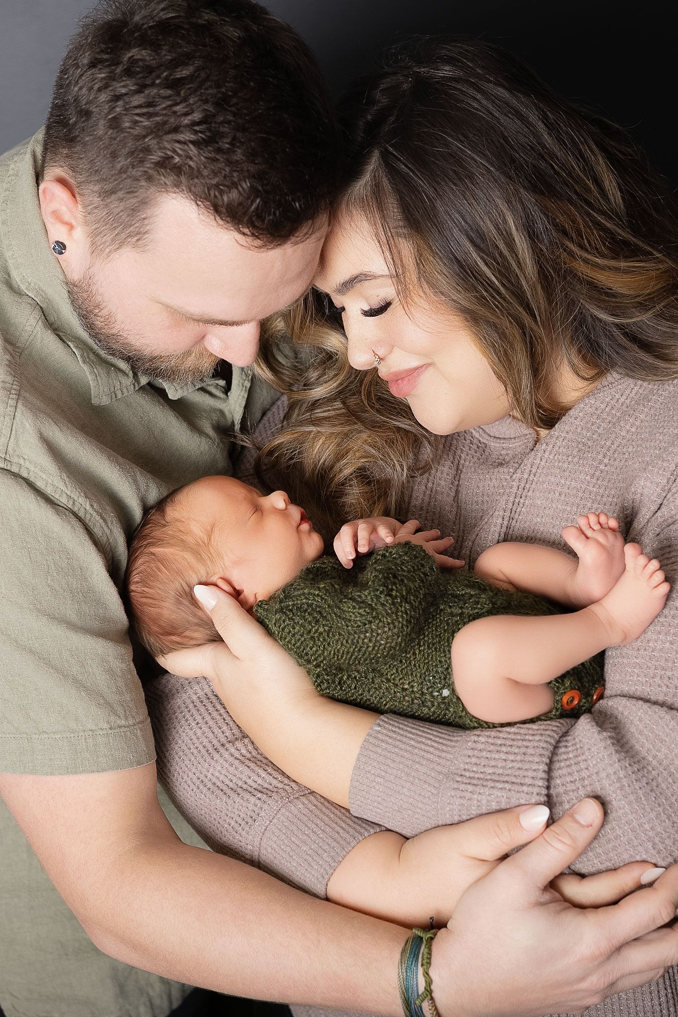 An intimate family portrait showing tender moments with a newborn baby in soft natural lighting.