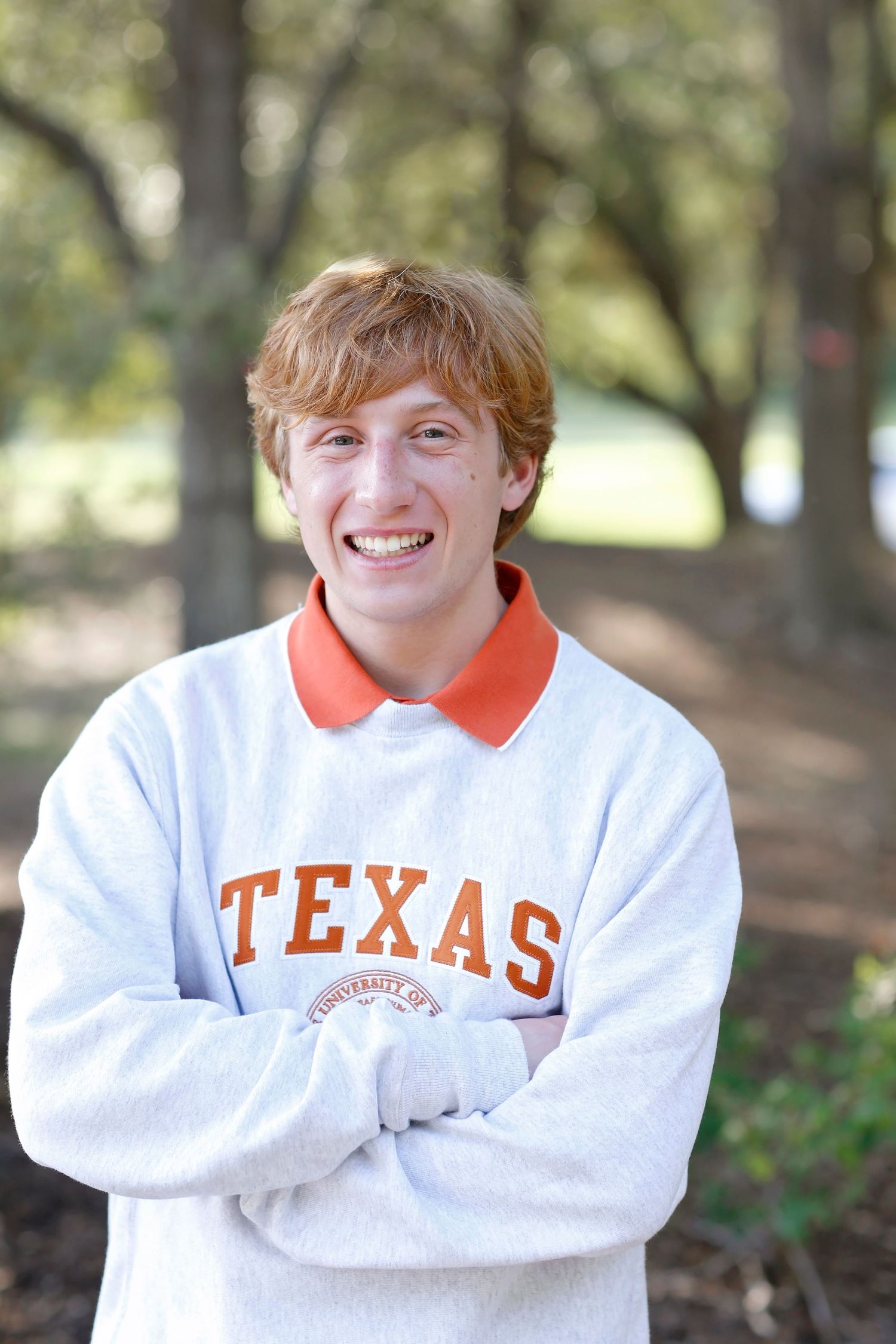 Student wearing Texas sweatshirt with orange collar poses outdoors.