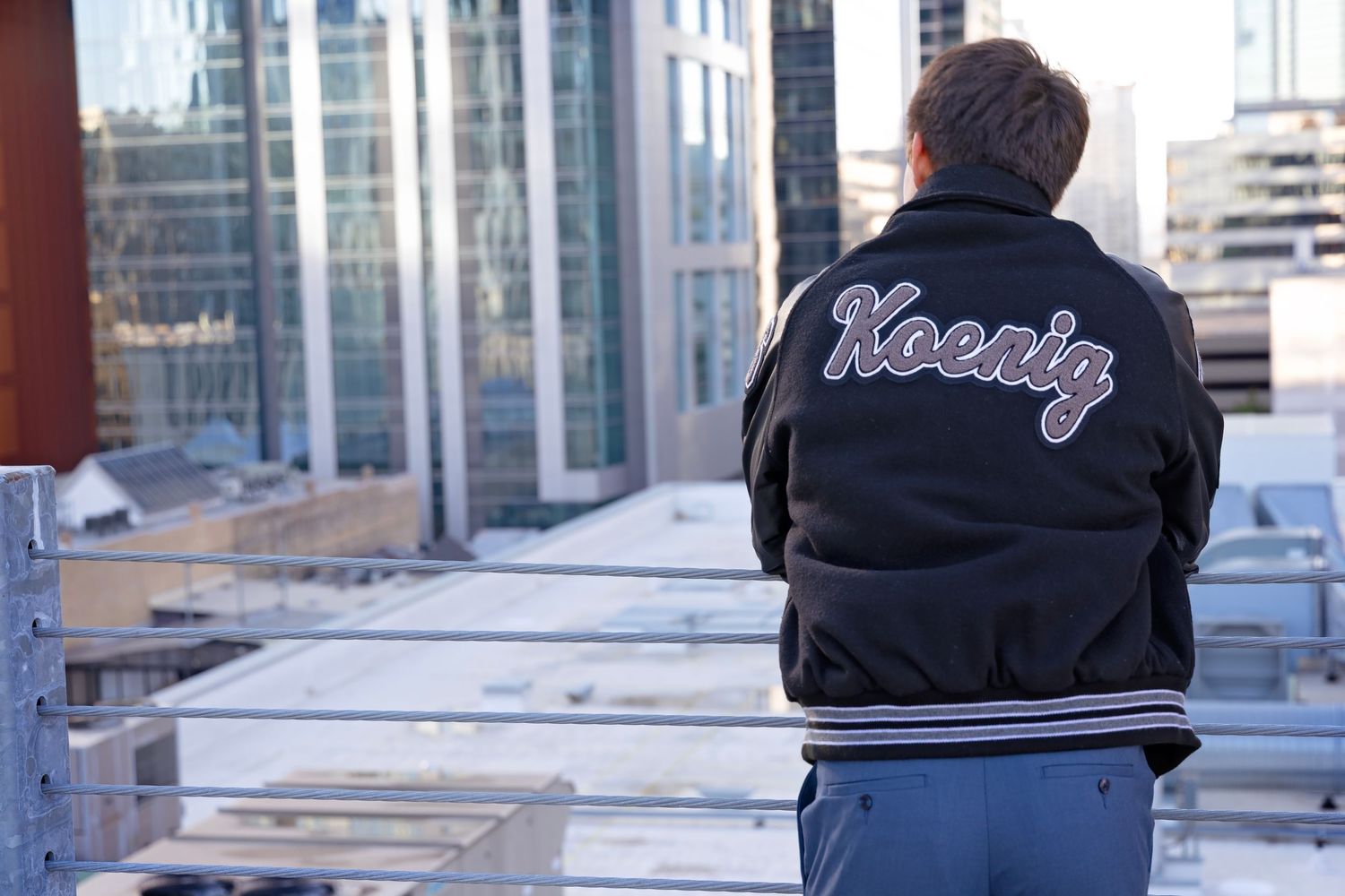 A black hoodie with white text 'Kooky' is shown from multiple angles on a glass display.