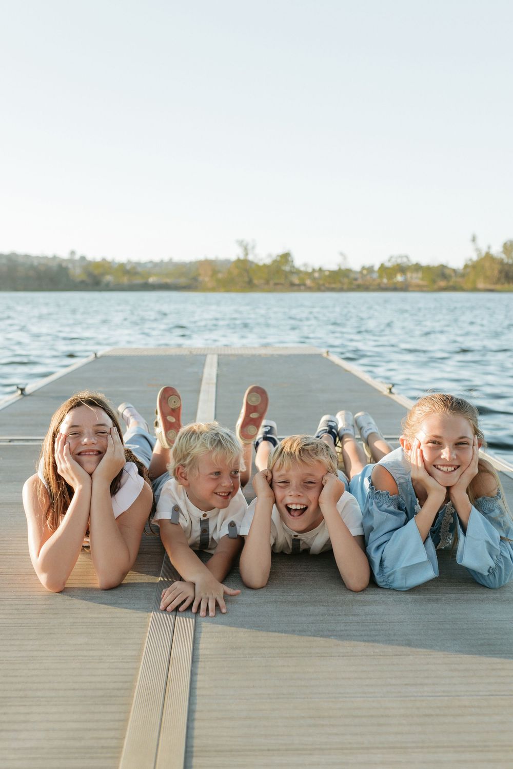 Four kids sit and smile while sitting on a dock at Lake Murray in La Mesa.