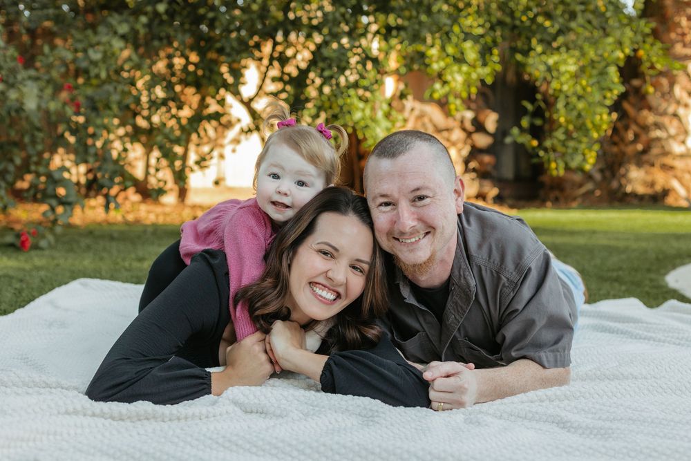 Family of 3 lays together on a blanket and smiles in Los Angeles.