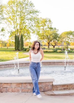 Senior girl session of girl standing by an outdoor fountain with water features and stone wall in Springfield, Missouri..