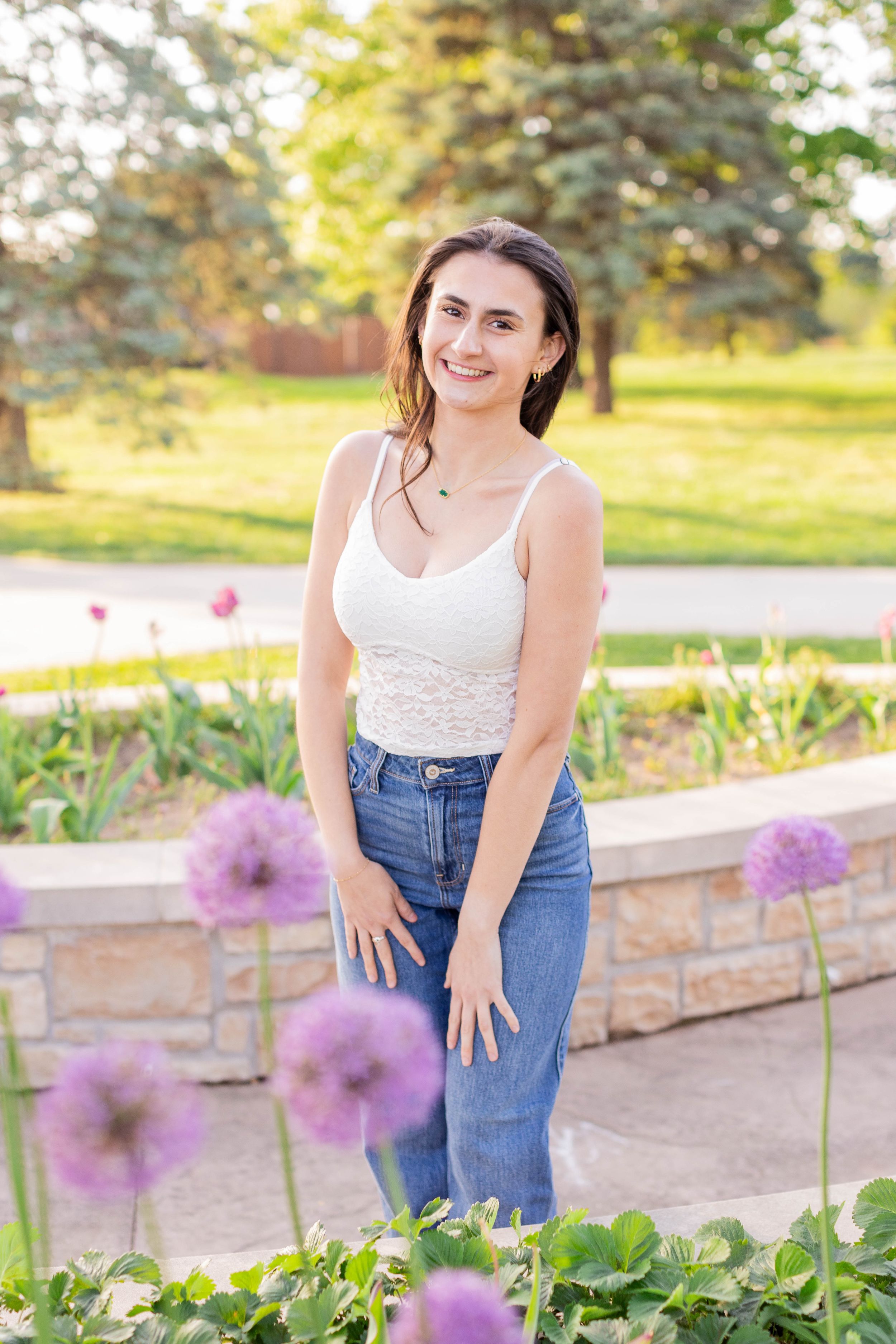 Senior girl session with girl standing in a beautiful spring garden scene with purple allium flowers in Springfield, Missouri.