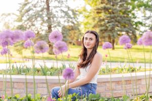 Senior girl session with girl standing next to purple allium flowers blooming in a garden in Springfield, Missouri.