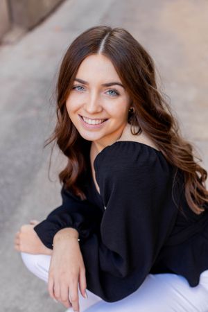 Senior session with girl with long dark wavy hair wearing a black top against a neutral background in Springfield, Missouri.
