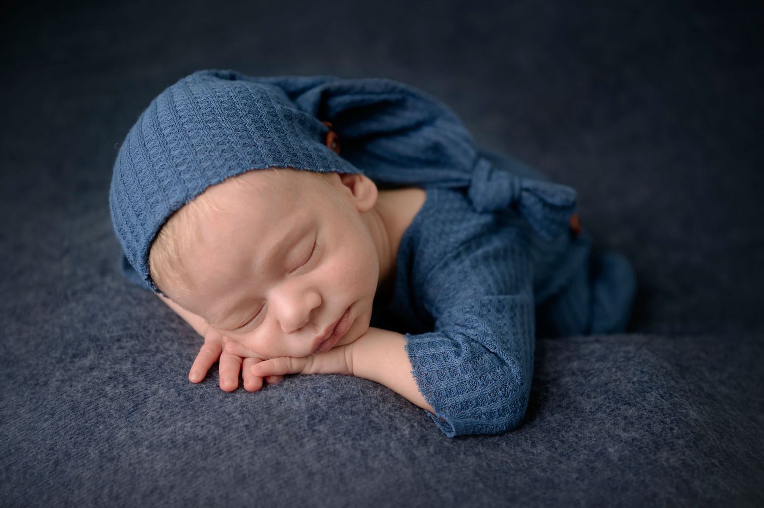 Newborn baby sleeping, baby in blue, with romper and hat, Natural styling during a weborn photography session in ashford kent