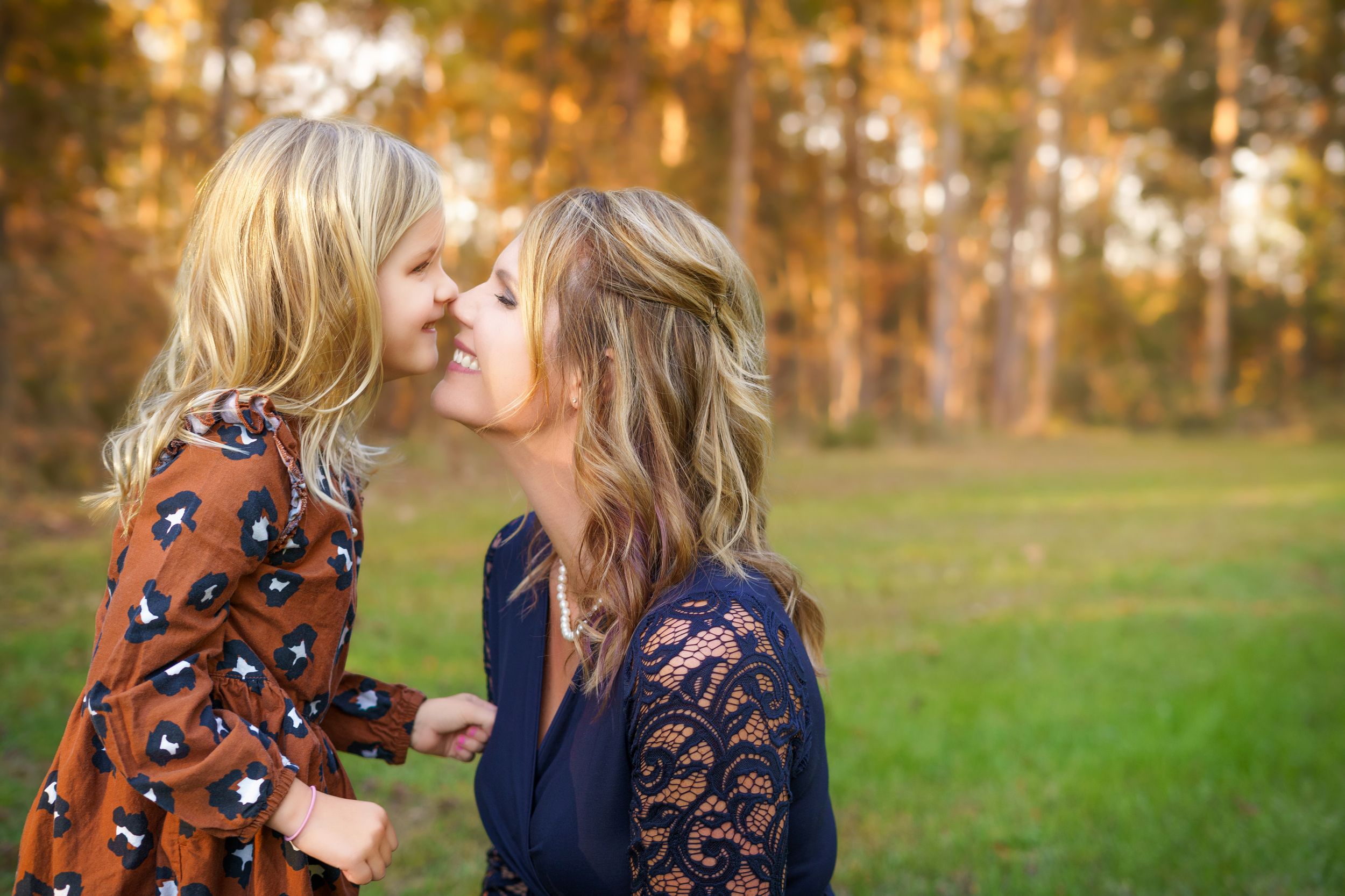 Mother and daughter sharing an Eskimo kiss surrounded by warm fall leaves, captured by boutique photographer Brandy Lee in Concord, NC.