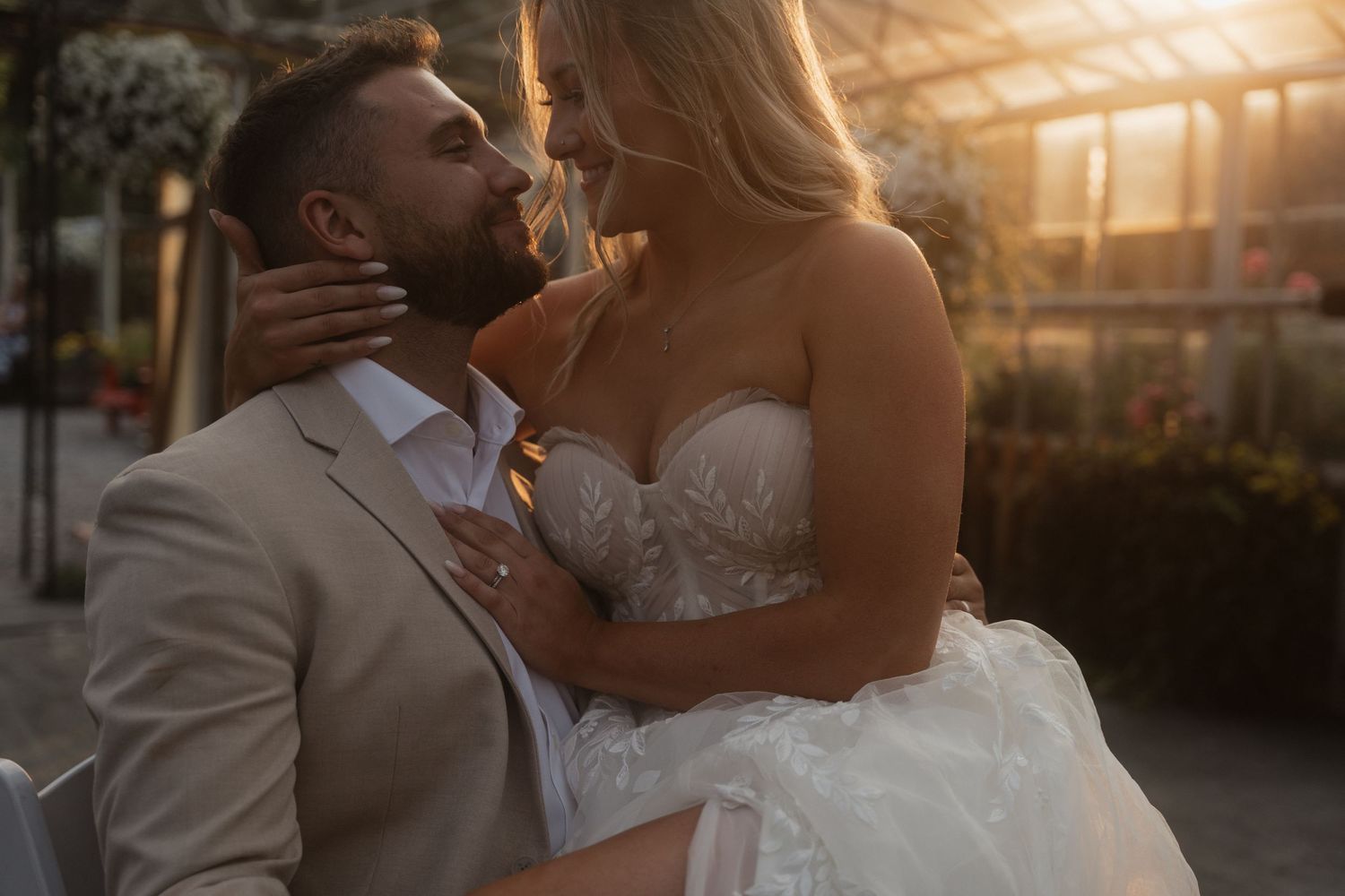 Romantic sunset portrait of newlyweds embracing in formal wedding attire.