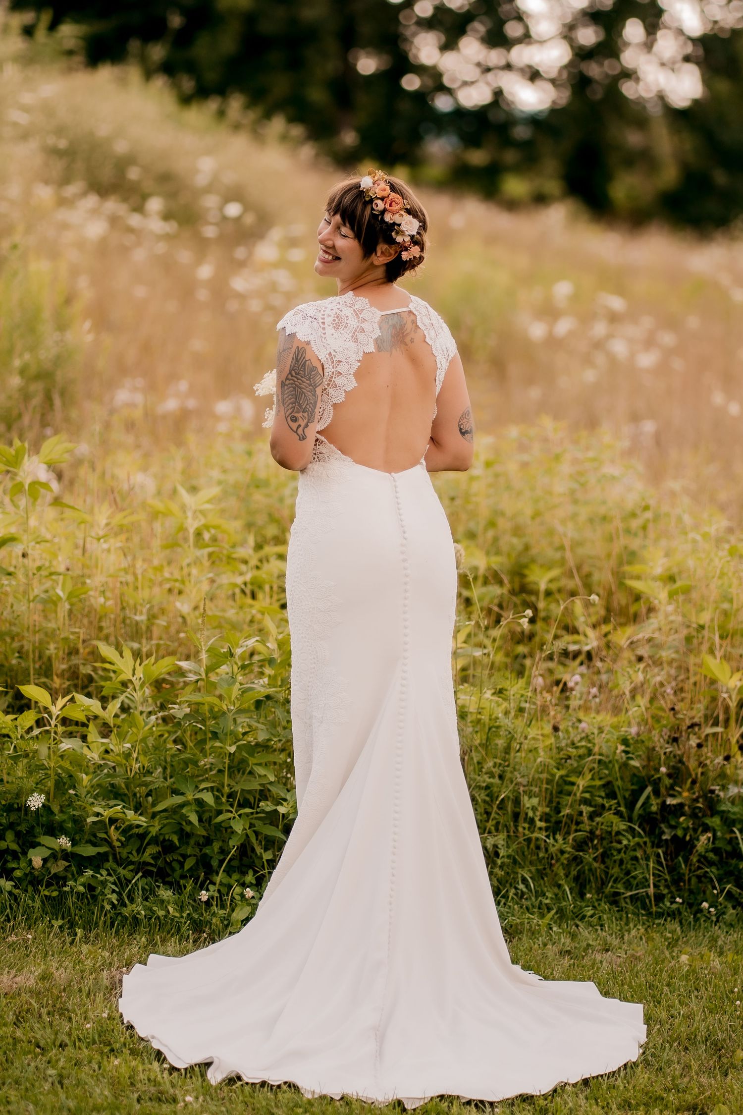 Beautiful lace wedding dress with train photographed from behind in a wildflower meadow.