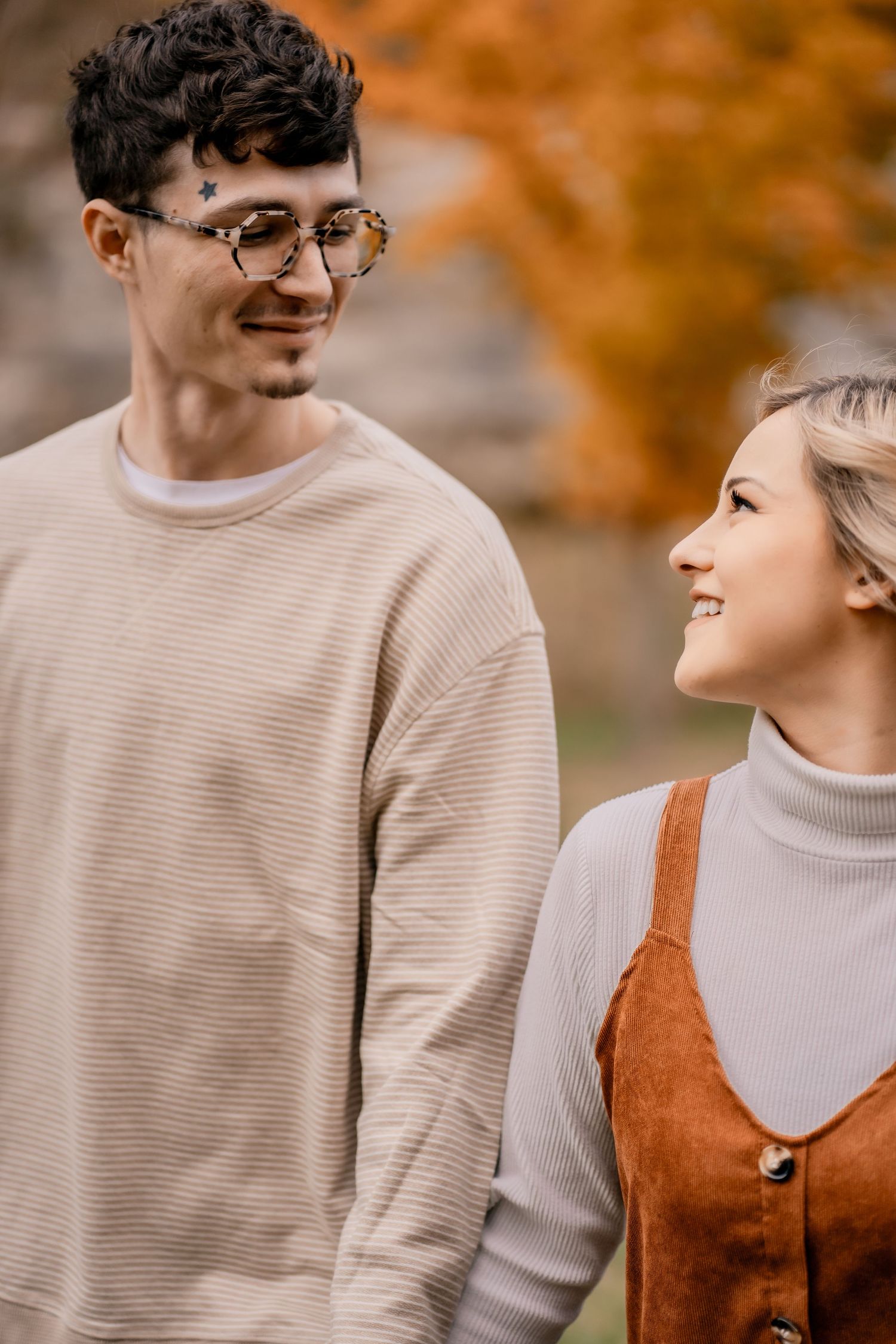 Romantic autumn portrait of a couple in cozy sweaters with fall foliage in background.