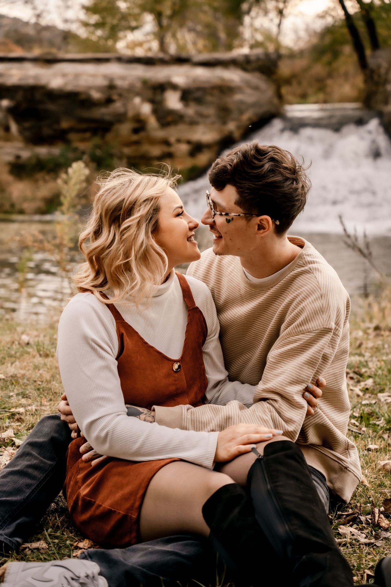 Intimate couple moment by a waterfall wearing matching neutral tones.