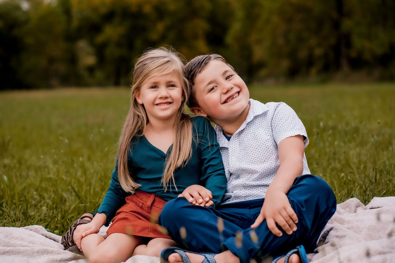 Candid family moment of children laughing and playing on grass.