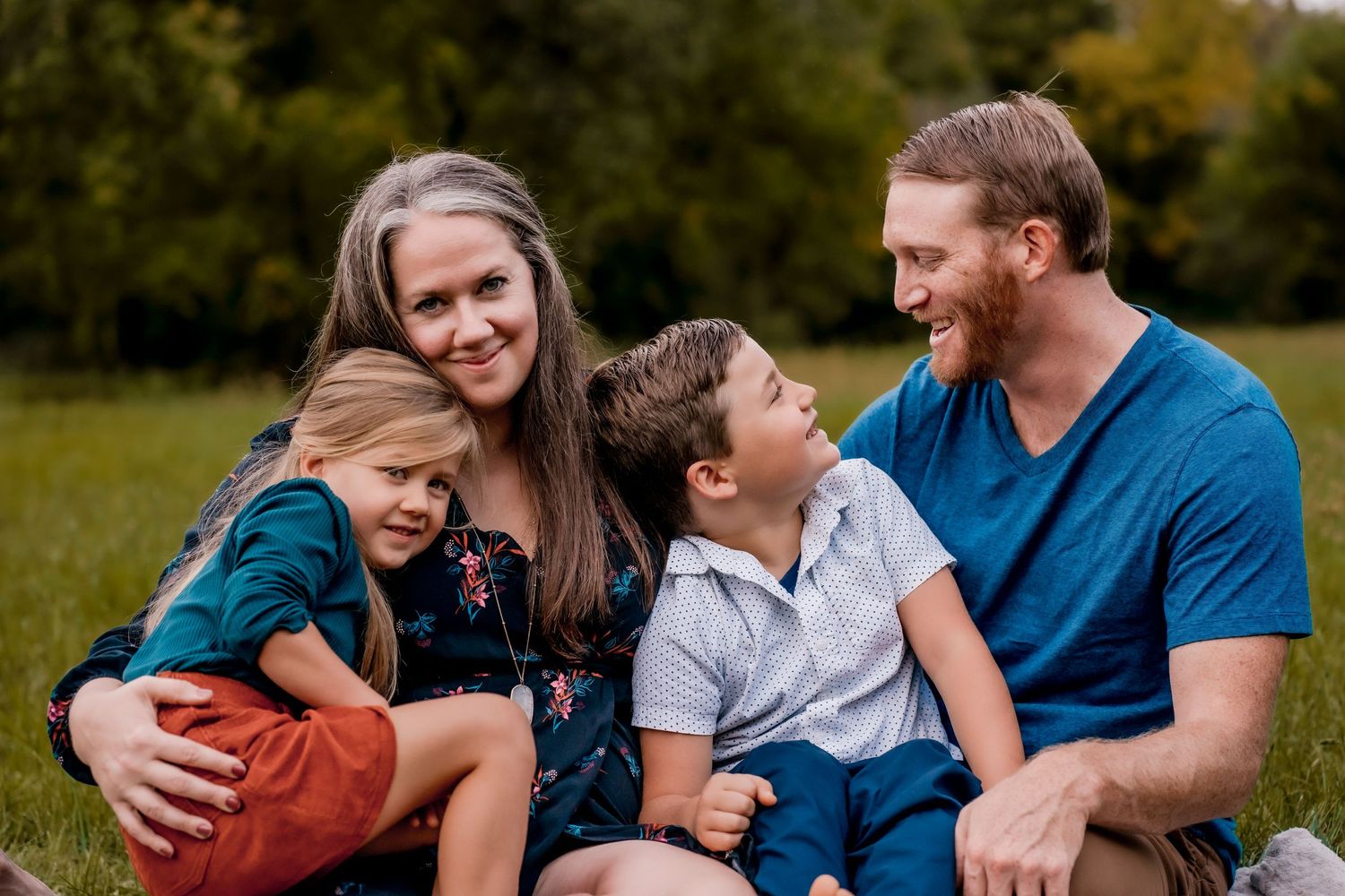 Family enjoying playful moments together on a grassy field during autumn.
