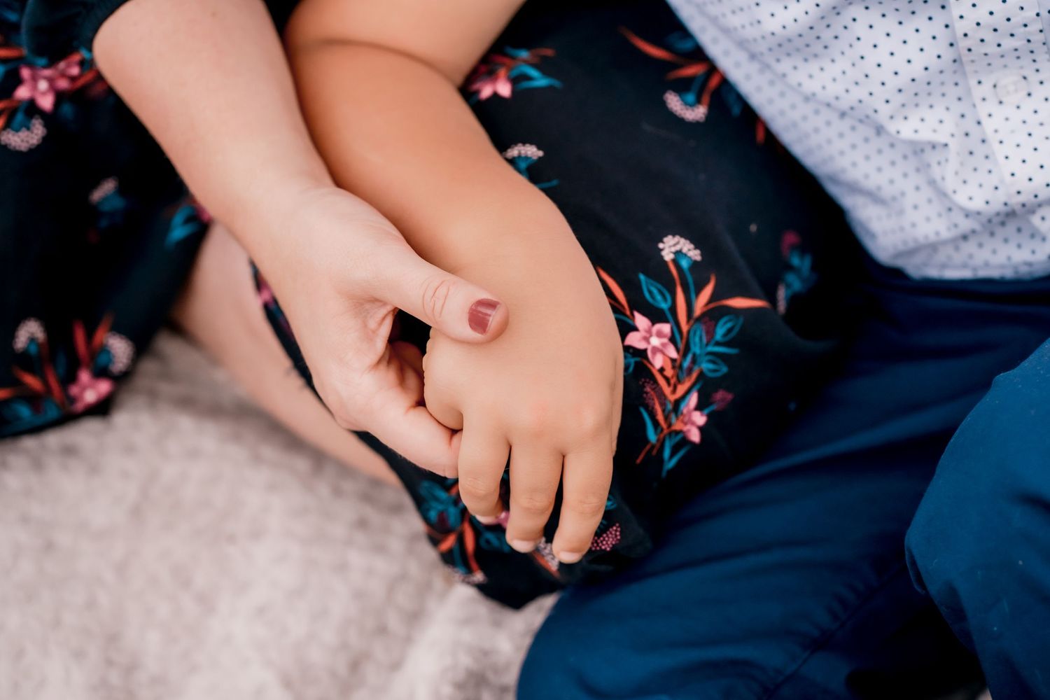 Close-up of hands holding a delicate engagement ring in natural outdoor lighting.