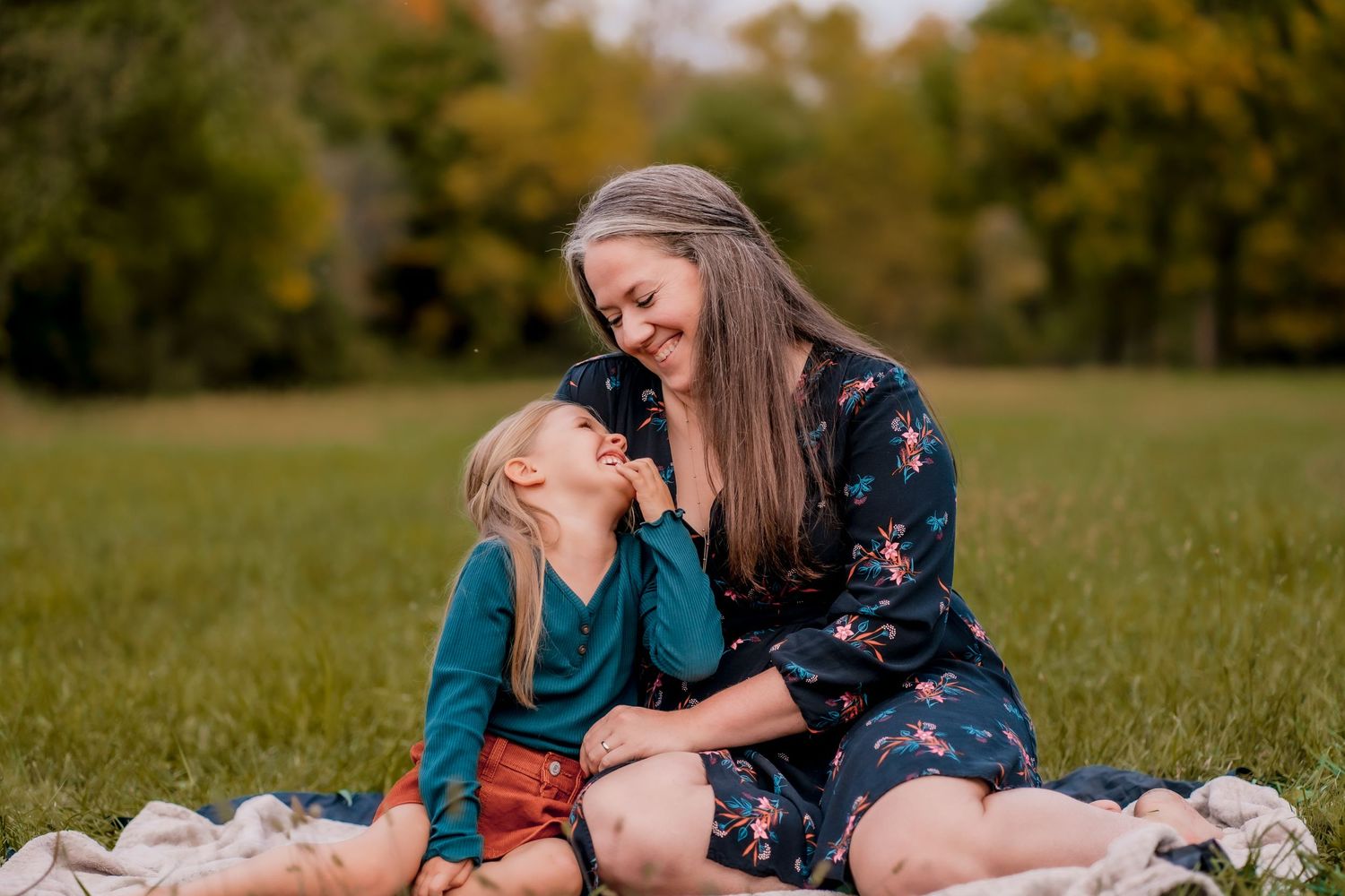 Mother and child share tender moments in a sunlit autumn field.
