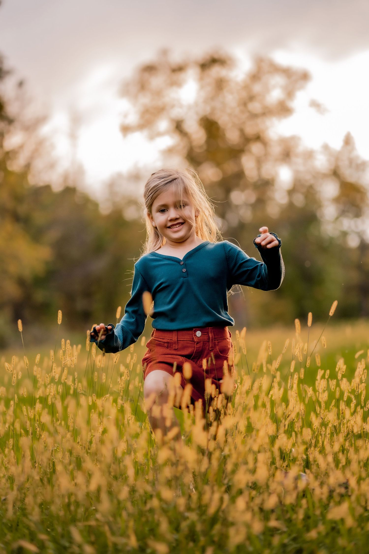 Child playing joyfully in a golden field of wildflowers at sunset.