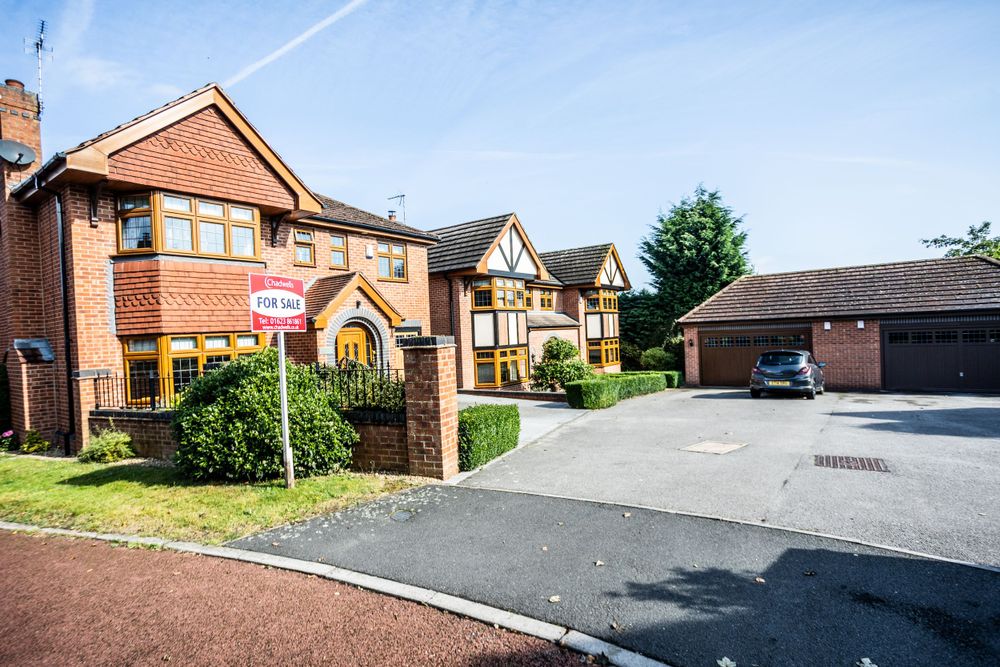 Residential street with modern red brick homes and shared parking area.