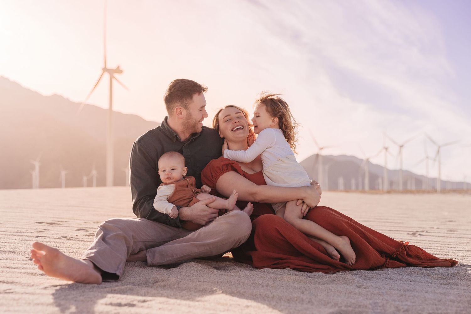 Family playing together on rocks during golden hour in nature.