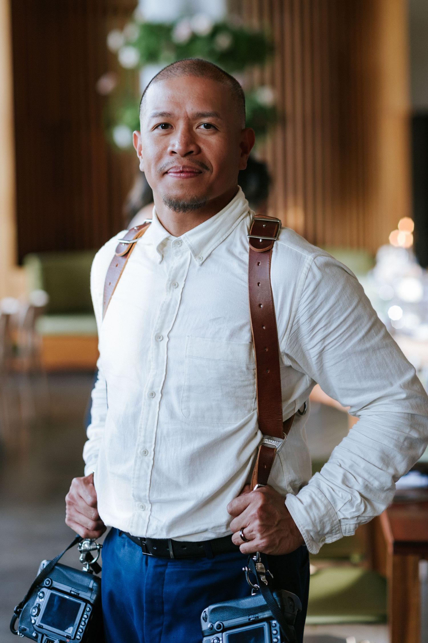 Professional wearing a crisp white shirt with leather suspenders in an elegant indoor setting.