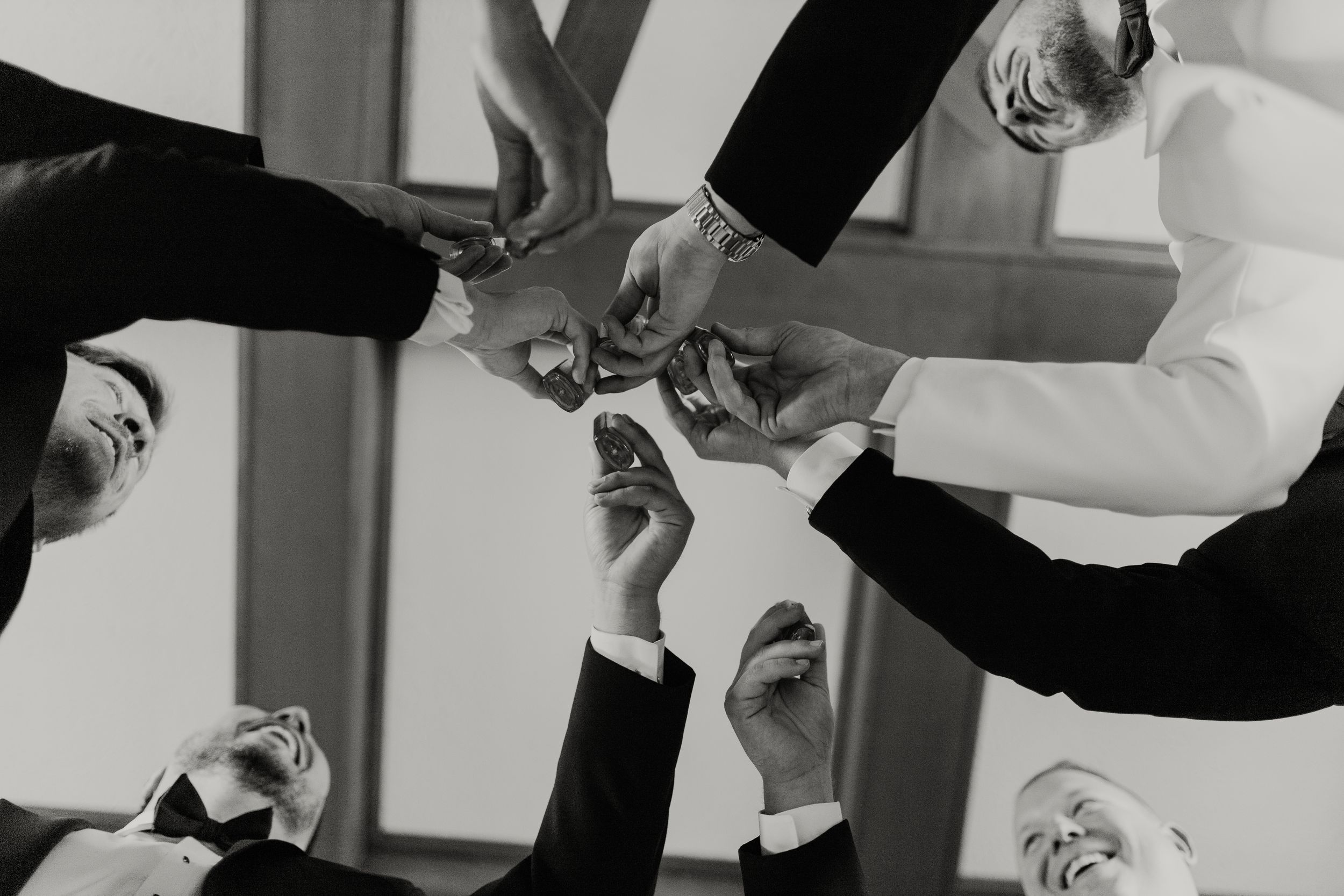 a shot of groomsmen clinking whiskey glasses from below