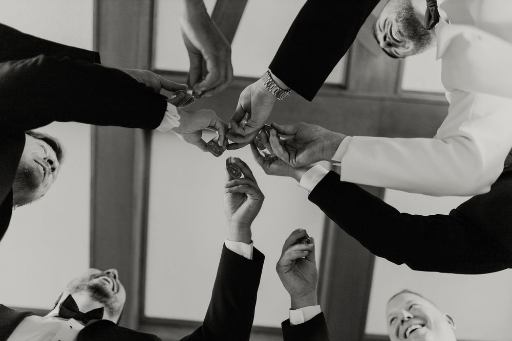 a shot of groomsmen clinking whiskey glasses from below